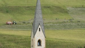 Die Georgskirche in Kals am Großglockner und im Hintergrund Bauern bei der Heuarbeit